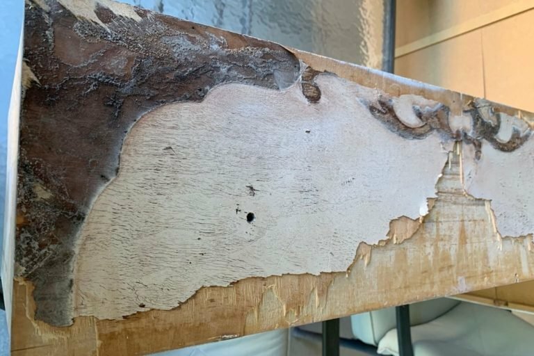 An image of damaged veneer being removed from a vintage dresser