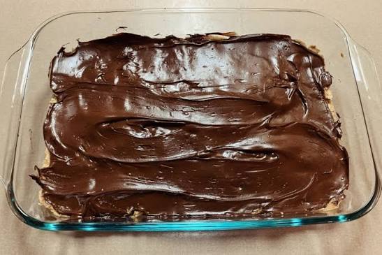 An image of melted chocolate poured over the peanut butter layer